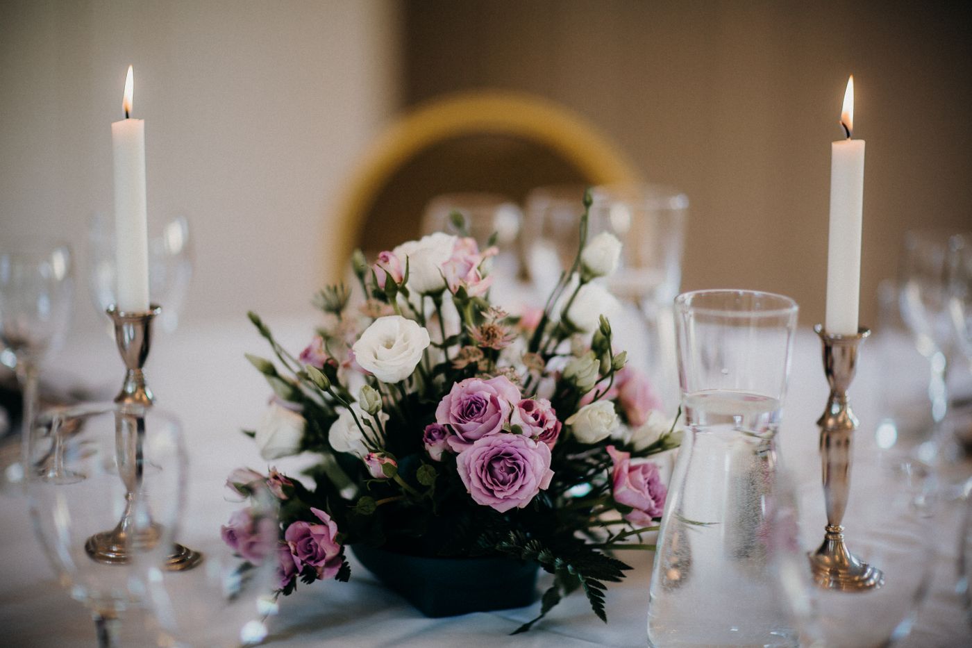 A reception table centrepiece of roses and taper candles