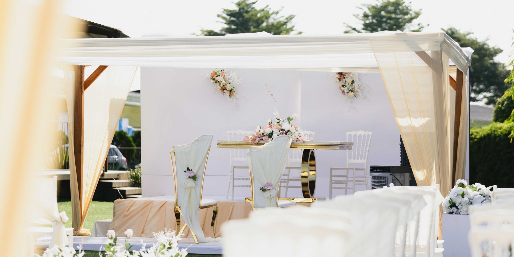 An outdoor ceremony set beneath a white draped canopy