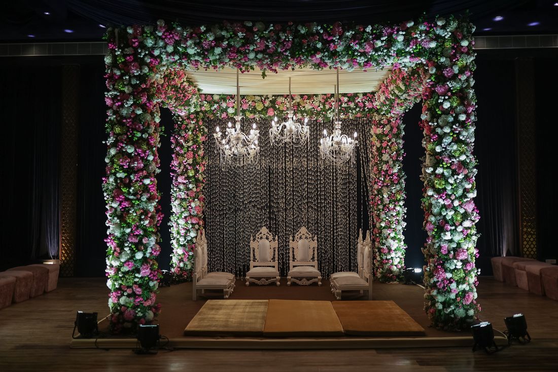 A floral mandap beneath chandeliers