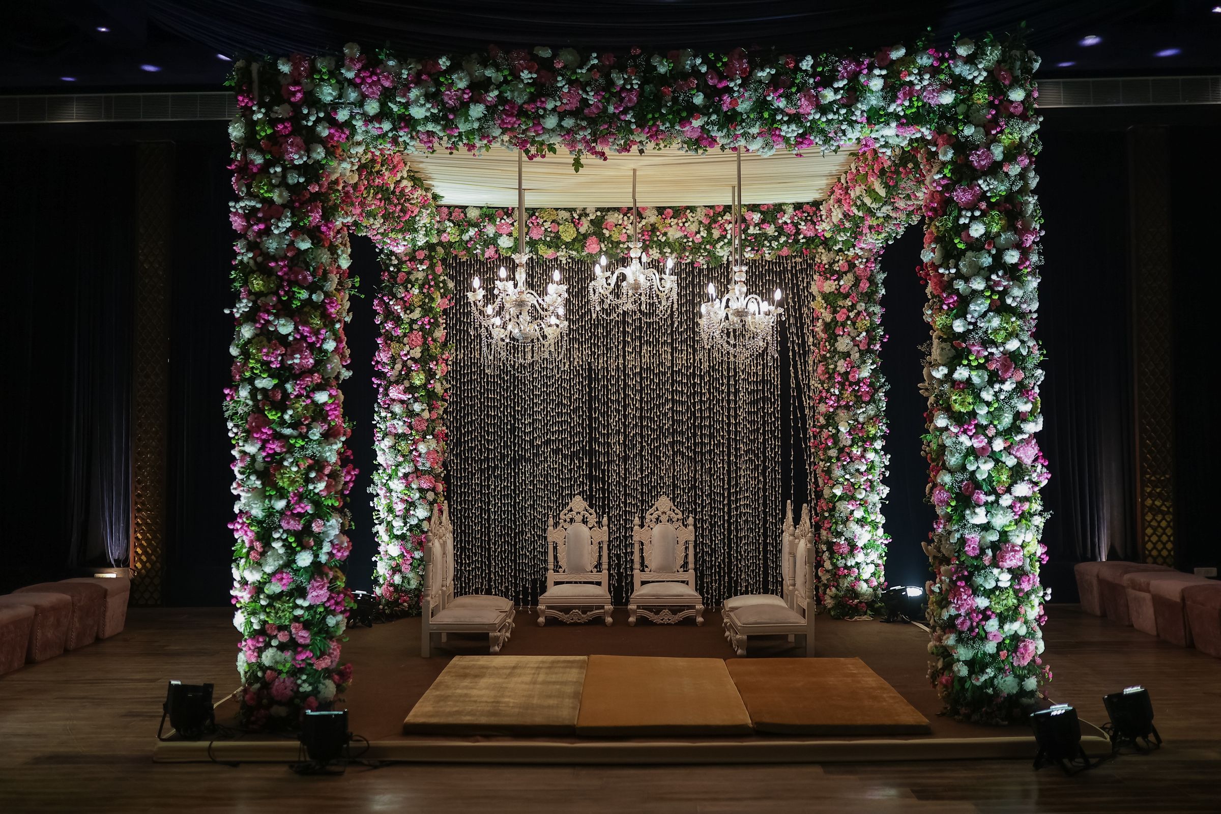 A floral mandap beneath a crystal chandelier, ready for a ceremony