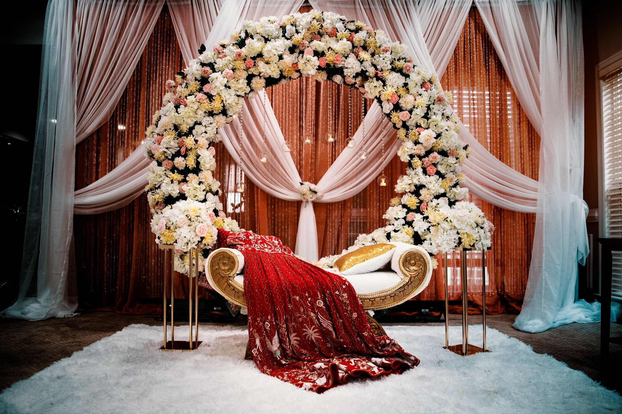 A floral arch and gilded seating prepared for a wedding stage